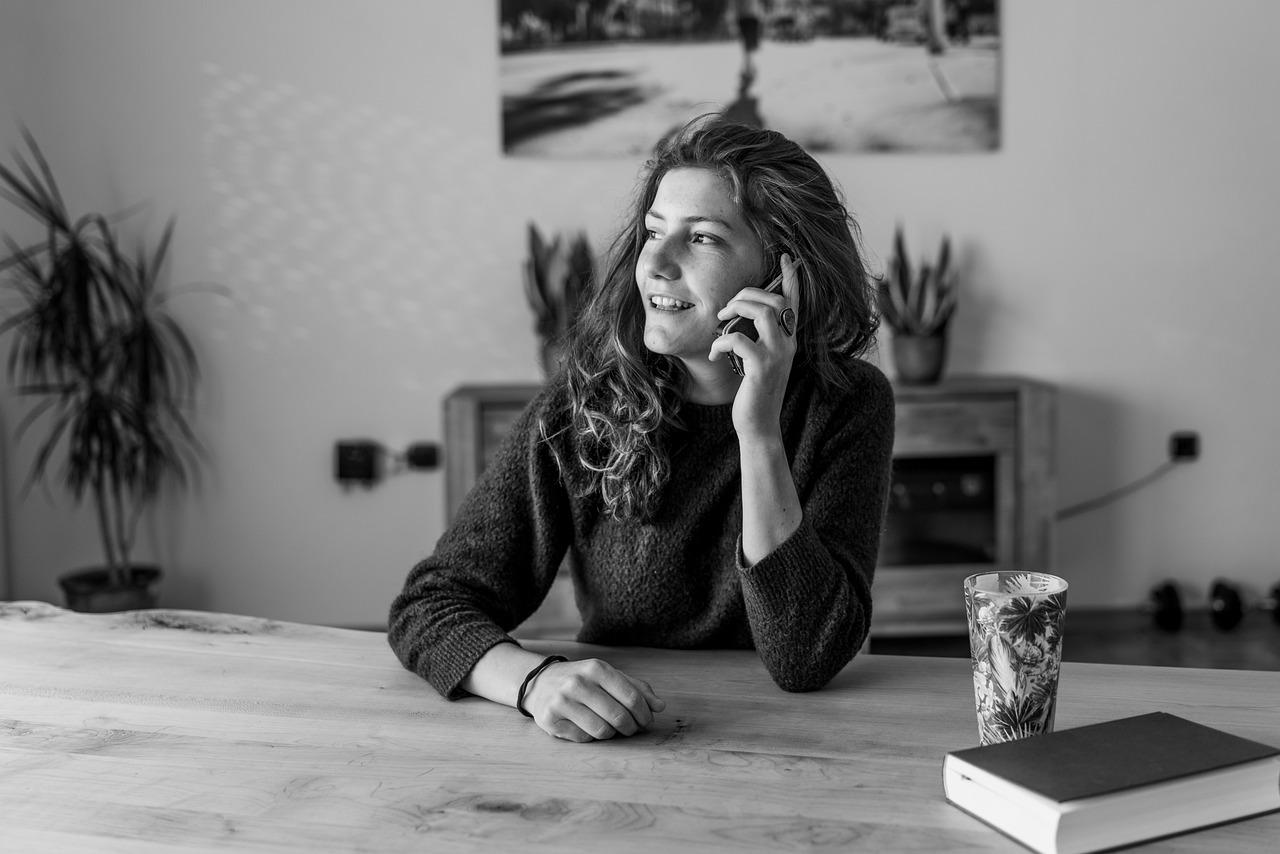 Kobieta siedząca przy stole i rozmawiająca przez telefon