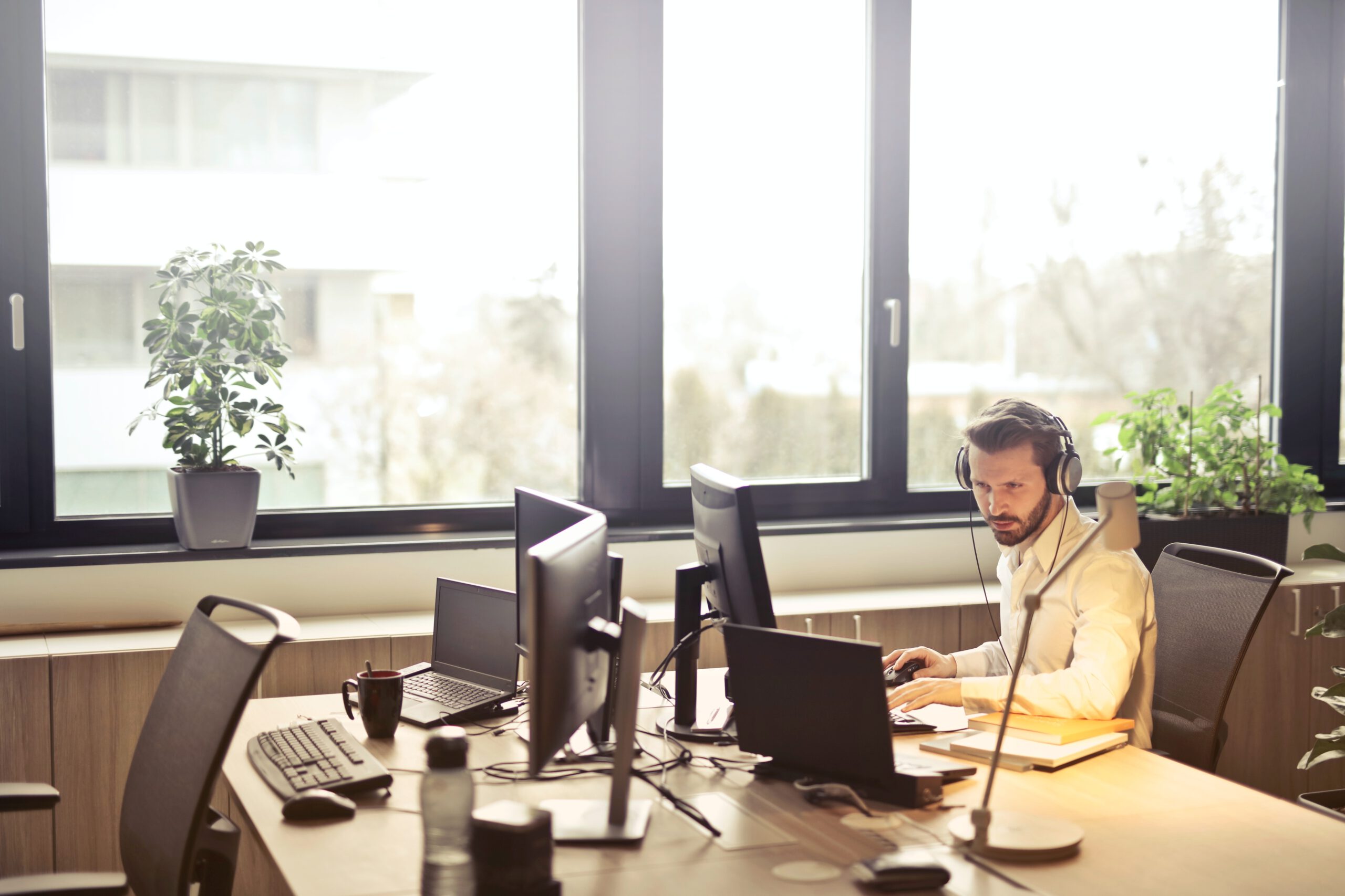 Mężczyzna pracujący na infolinii ze słuchawkami na uszach siedzący w biurze przed komputerem