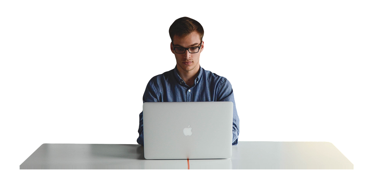 Mężczyzna siedzący przy stole i pracujący na laptopie na białym tle