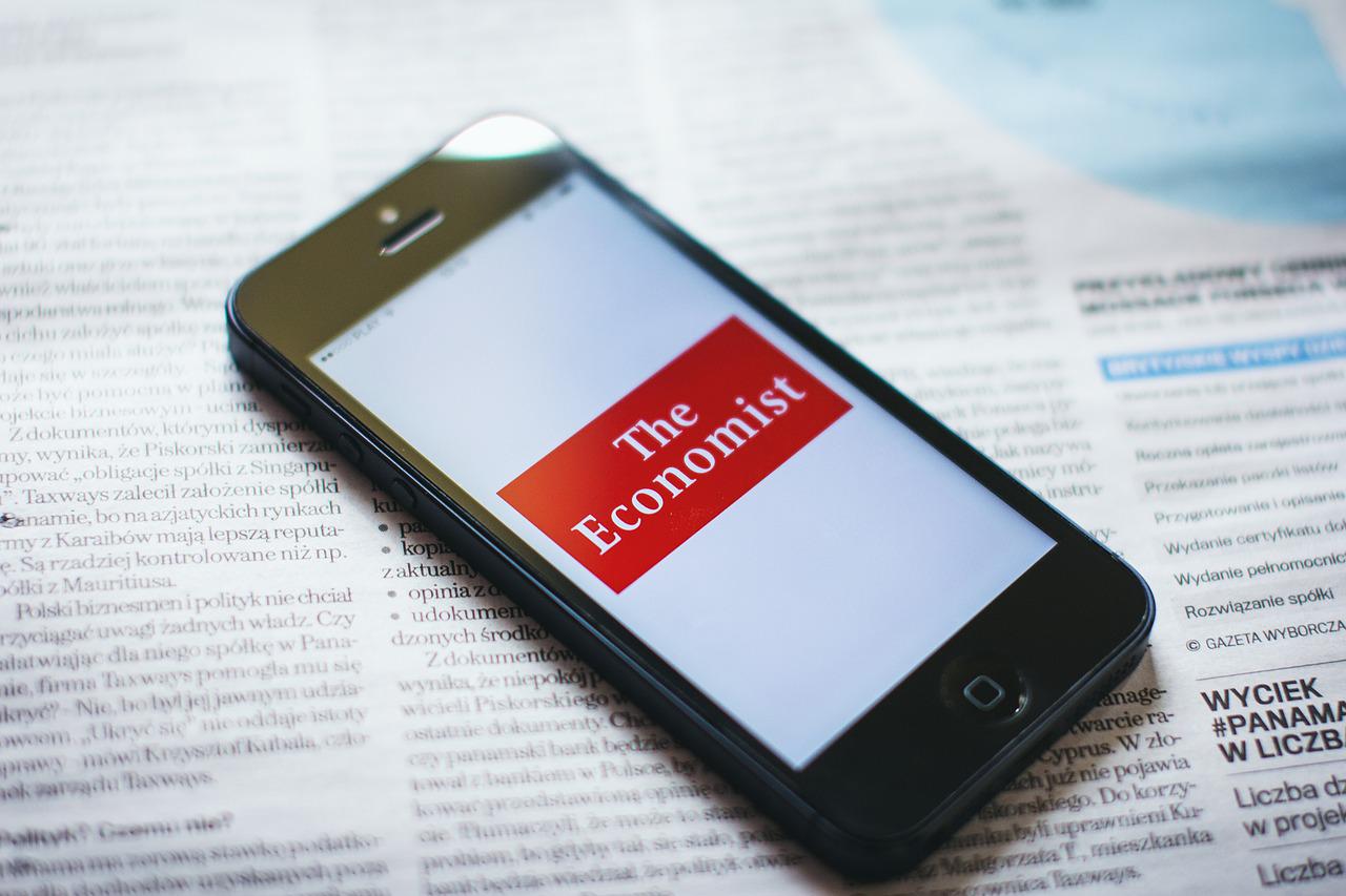 Telefon leżący na rozłożonej gazecie z wyświetlonym napisem The economist